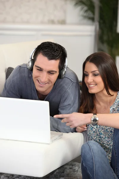 Un hombre escuchando música en la computadora con su esposa — Foto de Stock