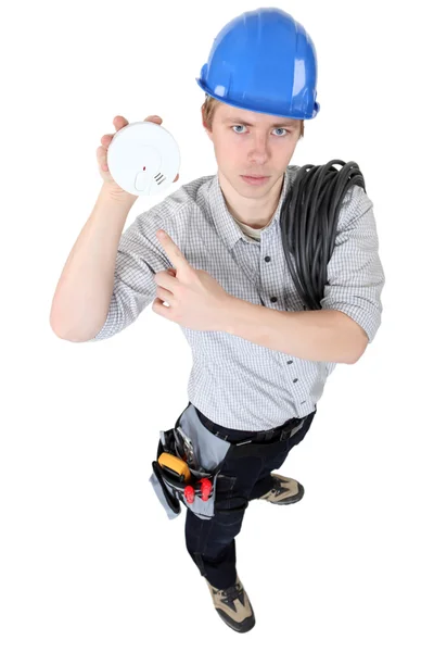 Un elettricista con un allarme antincendio . — Foto Stock
