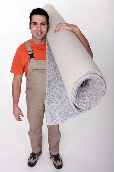 Obrero sonriente llevando alfombra — Foto de Stock