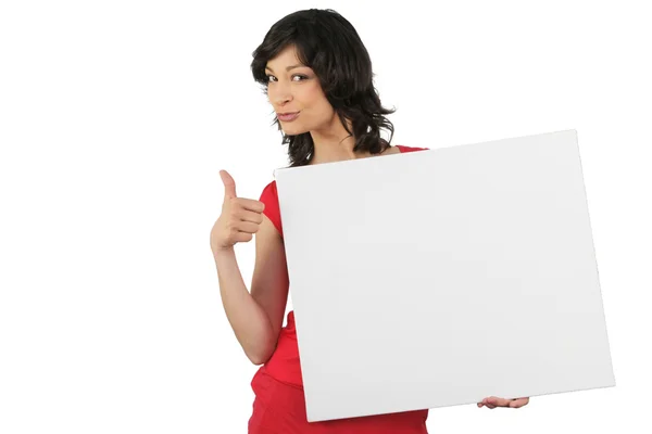Mulher atraente dando os polegares até uma placa deixada em branco para o seu messag — Fotografia de Stock