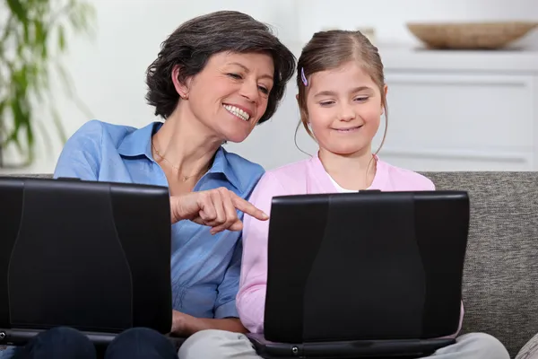 En mor och hennes dotter på sina bärbara datorer. — Stockfoto