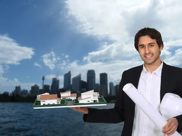 Architect holding model with urban landscape in background — Stock Photo, Image