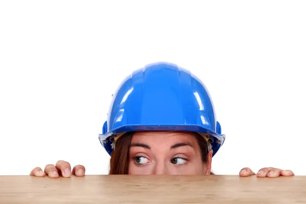 Handwerkerin lugt unter Tisch hervor — Stockfoto