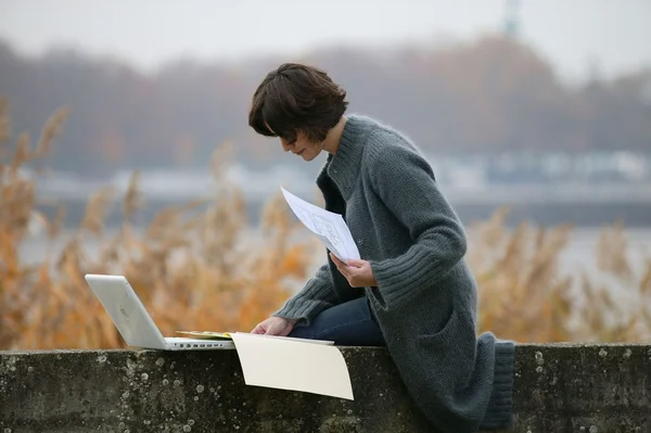 Woman sat on wall studying — Stock Photo, Image