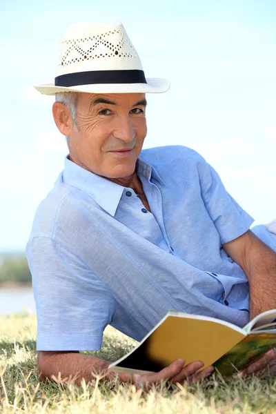 Man in hat reading in the park — Stock Photo, Image