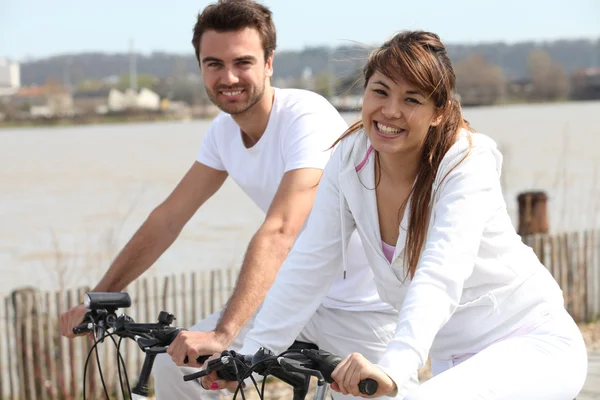 Giovane coppia che fa bicicletta vicino al mare — Foto Stock