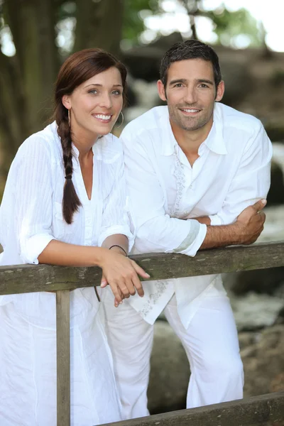 Par i vitt lutande på en land-staket — Stockfoto