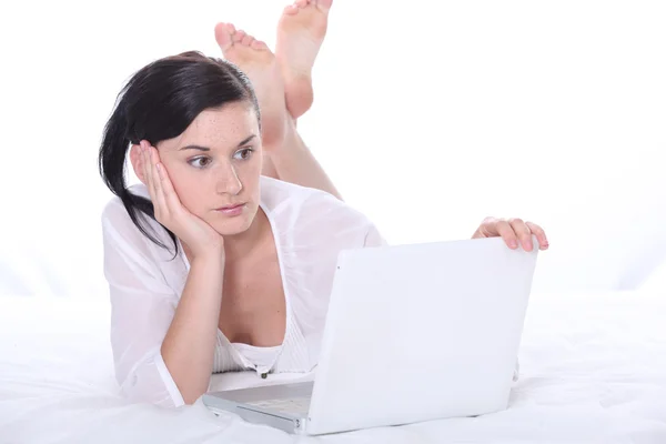Meisje gelegd op een bed met laptop — Stockfoto