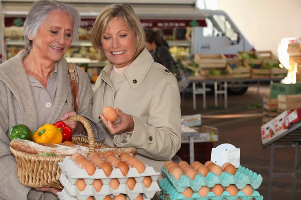 Zwei Seniorinnen kaufen auf dem Markt ein — Stockfoto