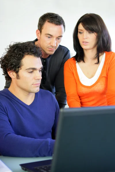 Tre lavoratori si sono riuniti intorno al computer portatile — Foto Stock