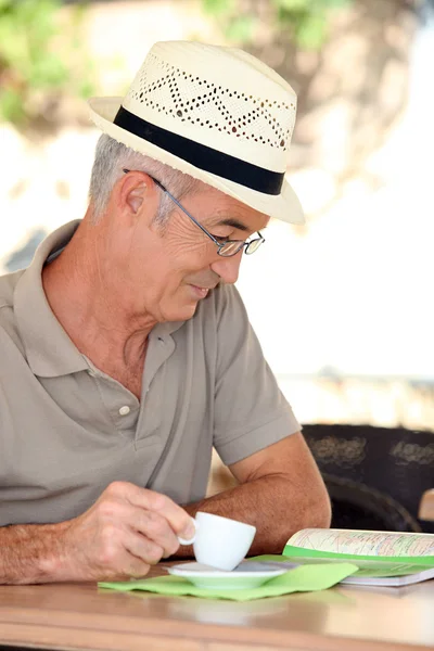 Uomo in pensione guardando una mappa mentre beve caffè — Foto Stock