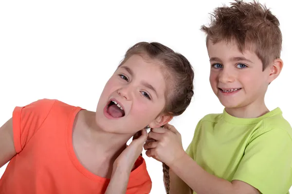 Мальчик дергает девочку за волосы — стоковое фото