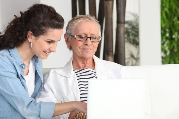 Jongere en oudere vrouw zitten op een laptop — Stockfoto
