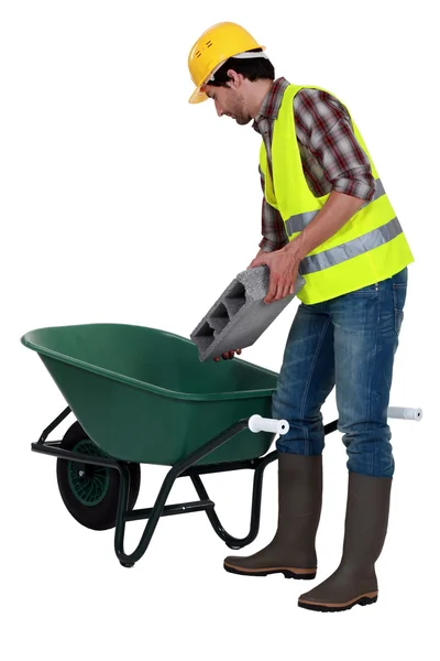 Worker putting a concrete block into a wheelbarrow — Stock Photo, Image
