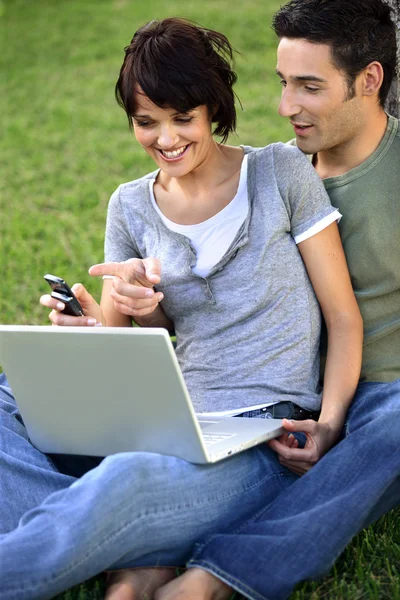 Couple sat in the park with laptop — Stock Photo, Image