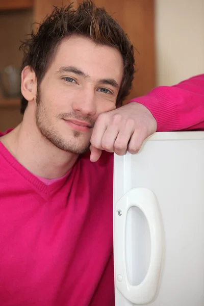 若い男が冷蔵庫のドアの上に腕でポーズ — ストック写真