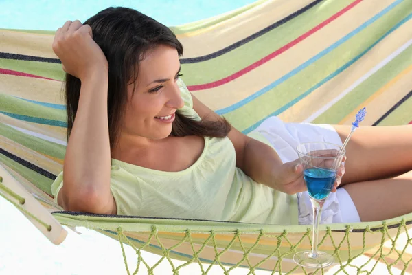 Frau trinkt Cocktail, während sie auf Hängematte liegt — Stockfoto