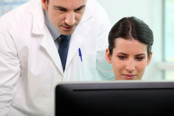 Verpleegster en arts kijken naar computerscherm — Stockfoto