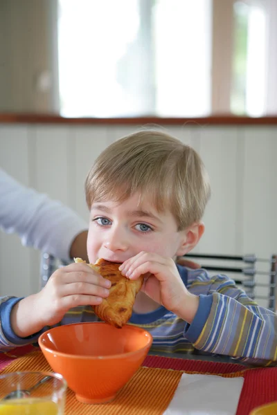 Kleiner Junge isst ein Croissant — Stockfoto
