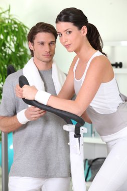 Woman on cross trainer with sports coach clipart