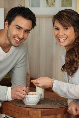 Young couple sharing a bowl of cornflakes clipart