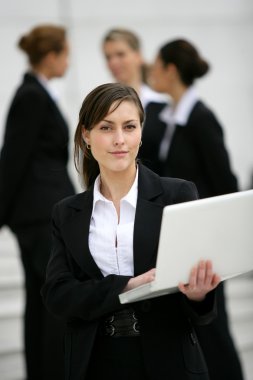 Businesswoman stood outdoors with colleagues in the background clipart