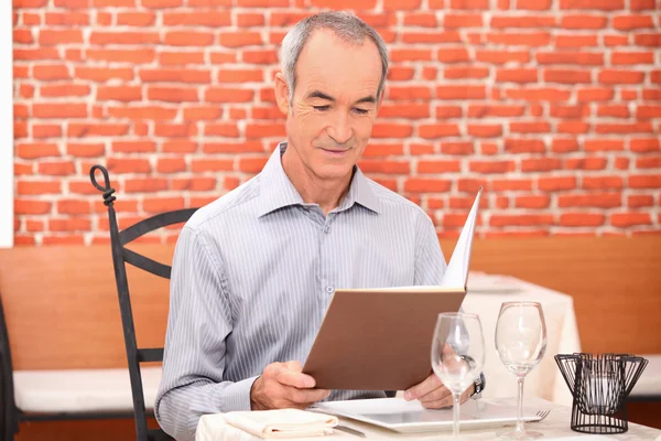 Homem olhando para um menu em um restaurante — Fotografia de Stock