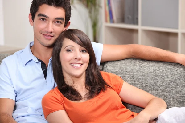 Jovem casal sentado em um sofá — Fotografia de Stock