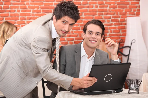 Hübsche junge Männer, die an einem Laptop arbeiten — Stockfoto