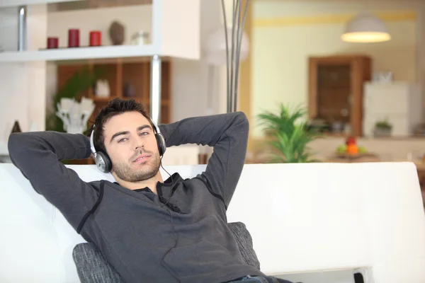 Man relaxing with music on sofa — Stock Photo, Image