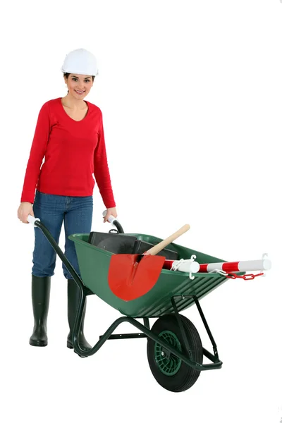 Mulher empurrando um carrinho de mão contendo suas ferramentas — Fotografia de Stock