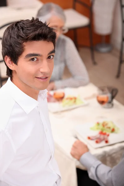 Junger Kellner serviert Mittagessen — Stockfoto