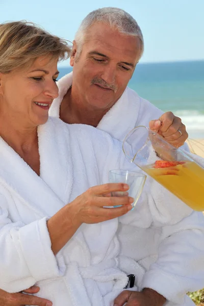 Casal tomando um copo de suco à beira-mar — Fotografia de Stock