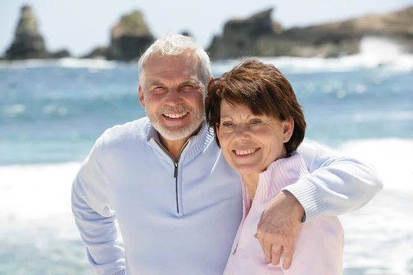 Old couple strolling along the beach — Stock Photo, Image