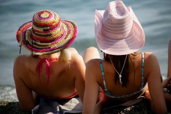 两个妇女坐在戴着帽子的在海滩上 — 图库照片