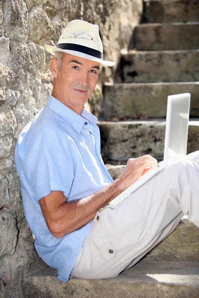 Elderly gentleman working outdoors on laptop — Stock Photo, Image