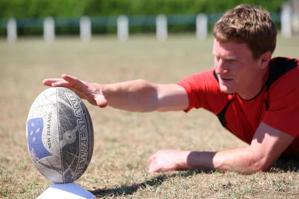 Muž připravuje rugby míč pro kick — Stock fotografie