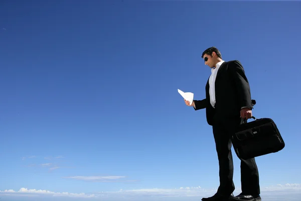 Üzletember, és egy táska egy kék ég ellen — Stock Fotó
