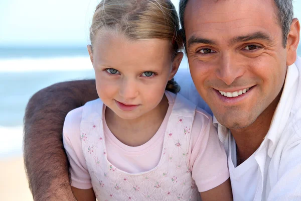 Padre e hija sentados juntos en la playa — Foto de Stock