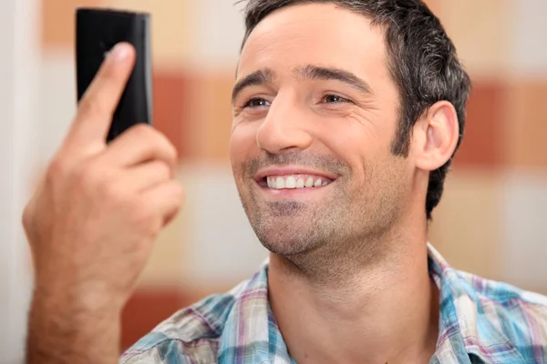Člověk při pohledu na telefon s úsměvem — Stock fotografie