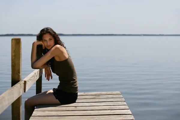 Donna seduta su un molo di legno — Foto Stock