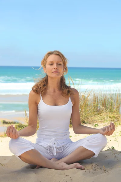 Kvinna mediterar på stranden — Stockfoto