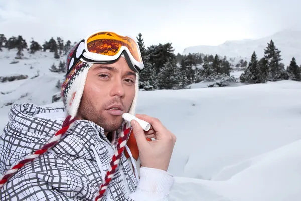 Retrato de um esquiador aplicando bálsamo labial — Fotografia de Stock