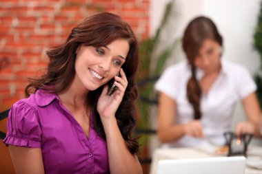 Woman in a restaurant on a mobile phone clipart