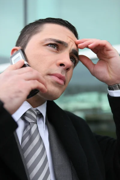 Primer plano de joven hombre de negocios en el teléfono buscando preocupado —  Fotos de Stock