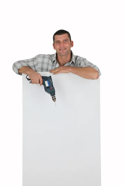 Homem com broca apoiada em um sinal branco — Fotografia de Stock