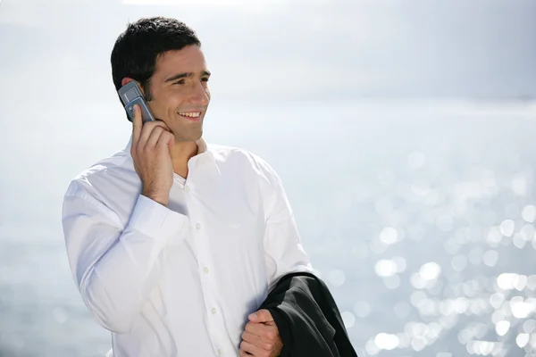 Empresario haciendo una llamada en la playa — Foto de Stock