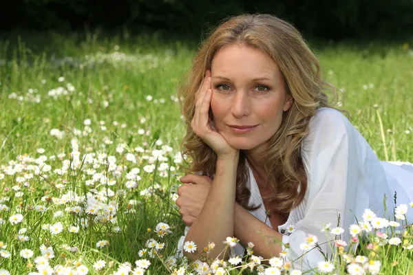 Vrouw vaststelling in veld vol met bloemen — Stockfoto