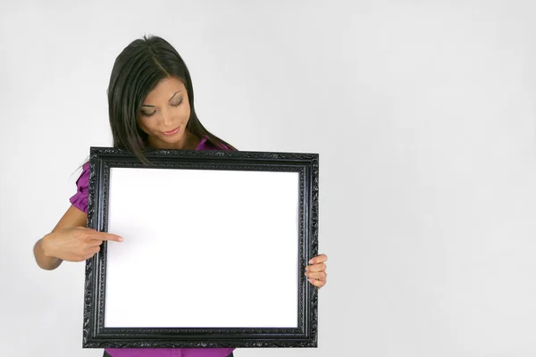 Woman pointing to empty picture frame — Stock Photo, Image