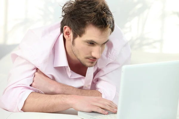 Jonge man liggen voor laptop — Stockfoto